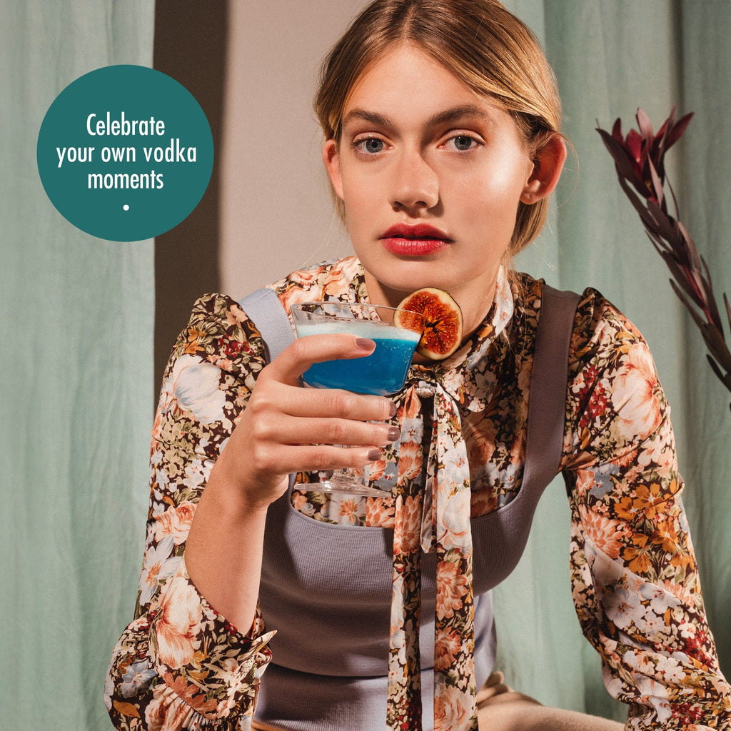 young women holding blue cocktail drink decorated with fig, celebrate your own vodka moments